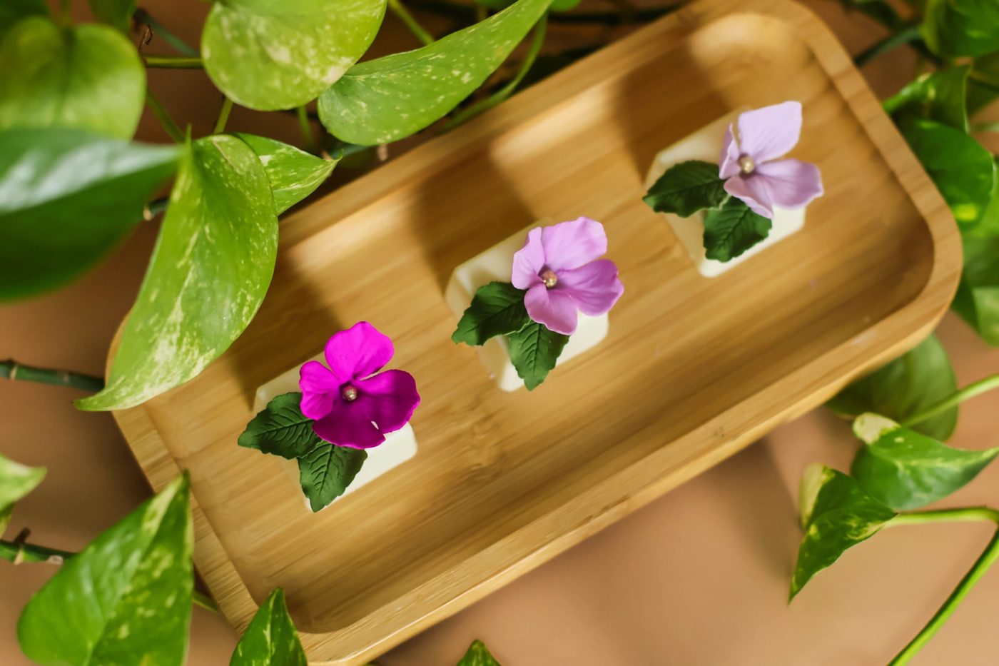 Três doces finos com violetas de açúcar e folhas